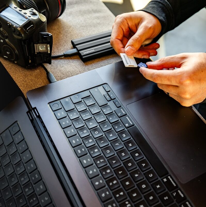 Hands inserting sd card into laptop reader